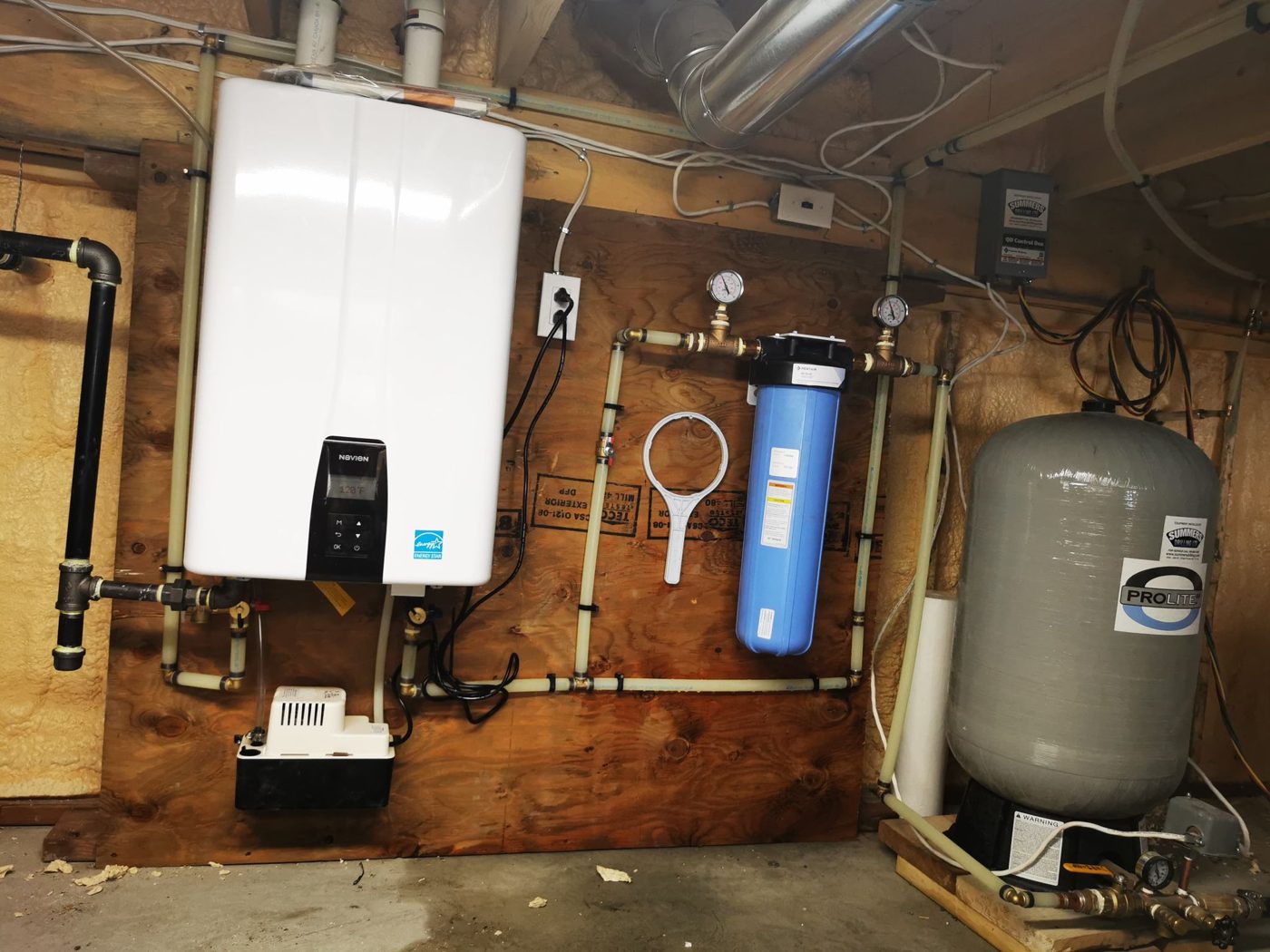 Tankless water heater, filtration and pressure tank installed on a basement wall