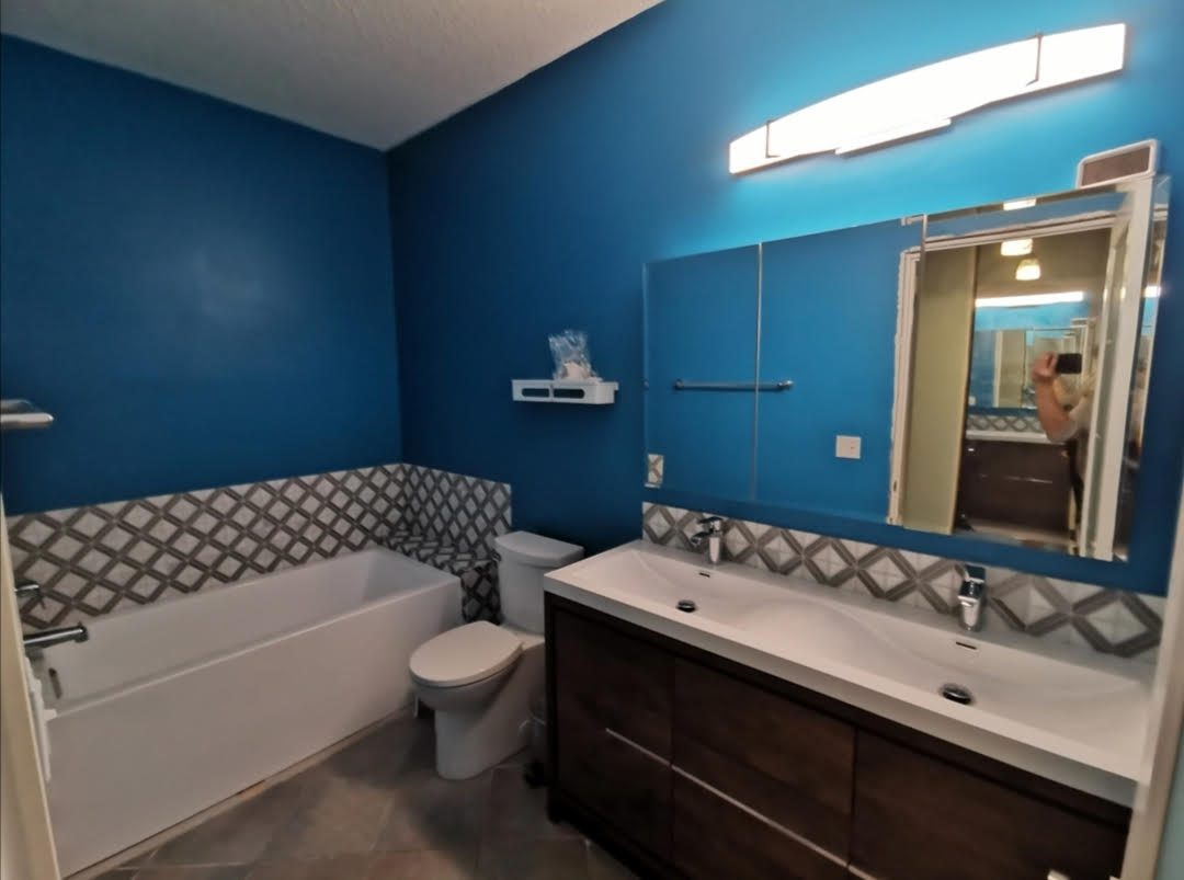 Renovated bathroom with a teal accent wall, new tub, toilet and double vanity