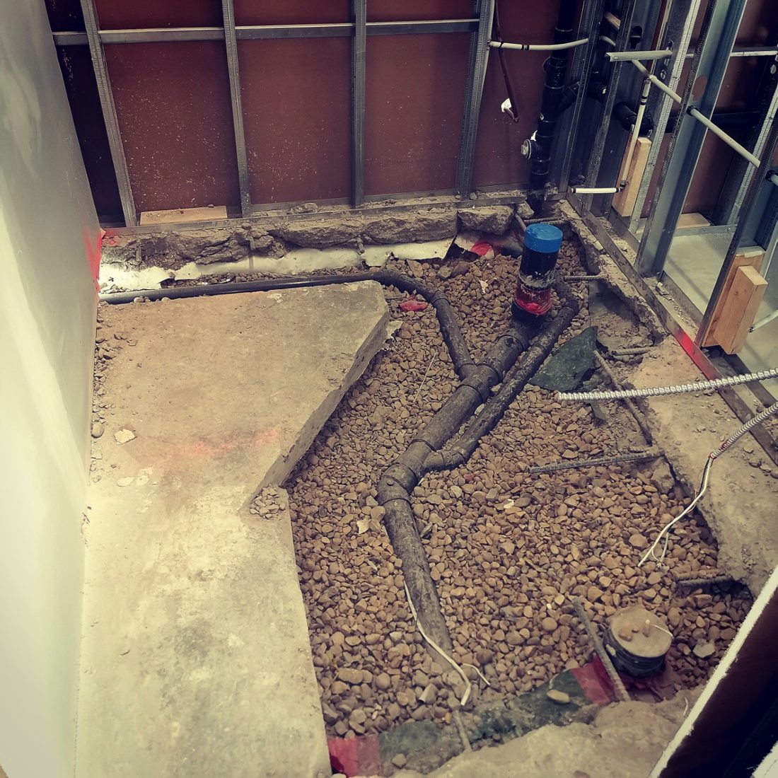 Open concrete floor with new drain lines during a basement renovation
